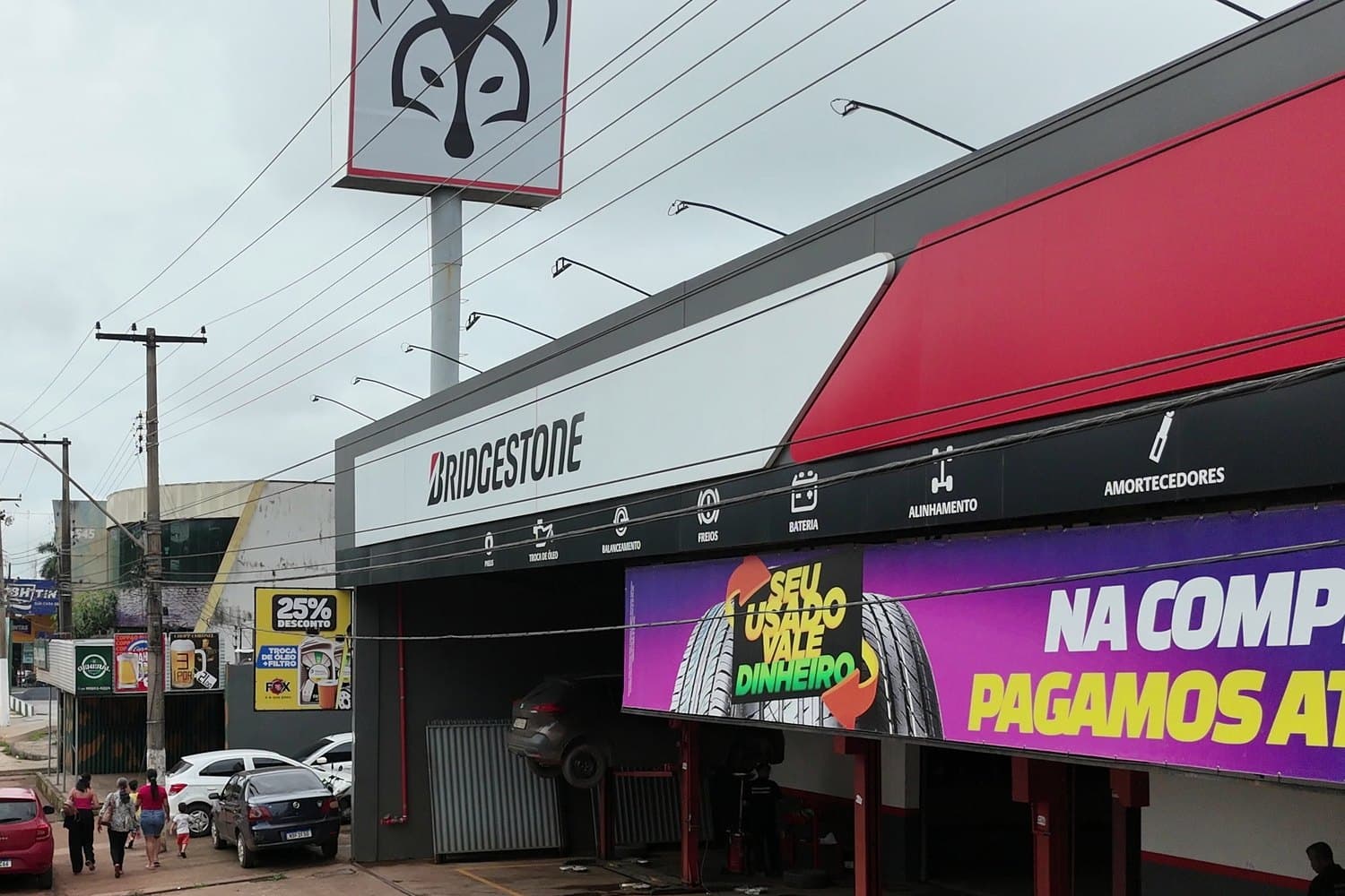 Fachada de uma loja da Rede Fox na avenida, com o totem da raposa e a oficina aberta